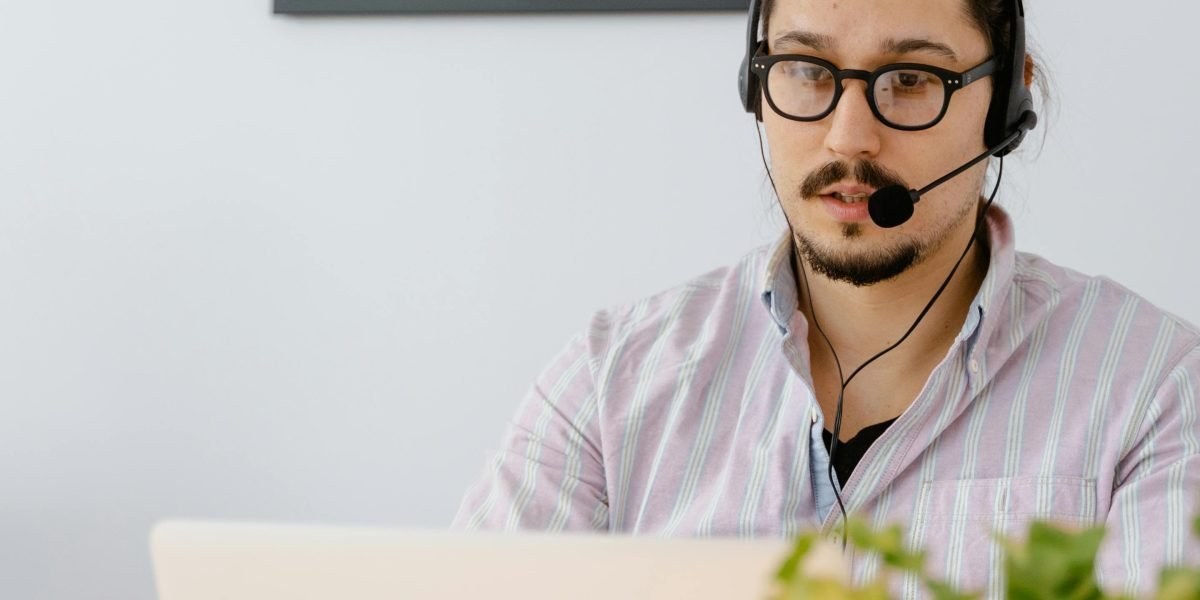 Remote sales professional using a laptop and headset in a home office